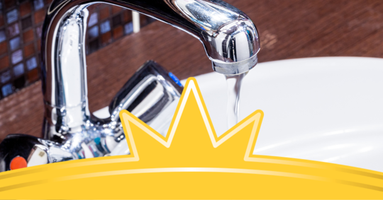 A close up image of a modern chrome bathroom sink with a running faucet.